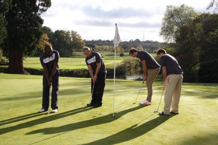 London Irish stars (from left) Topsy Ojo, Shane Geraghty, Bryn Evans and Darren Allinson putting out on the Par-3 18th signature hole of Burhill Golf Club’s New Course.