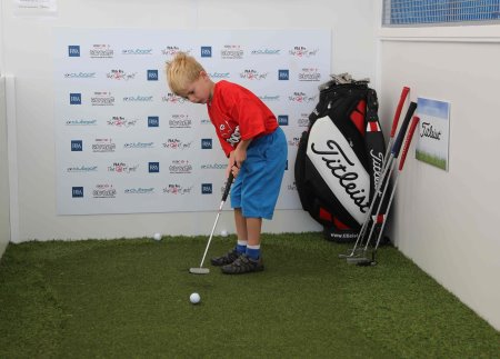 A young golfer concentrating hard on the putting challenge supported by Titleist