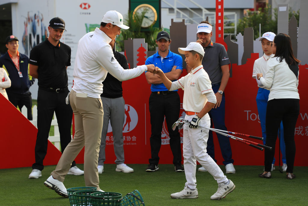 SHANGHAI, CHINA - OCTOBER 29:  Haotong Li of China, fist bumps with a youngster at a clinic for junior golfers during practice prior to the WGC HSBC Champions at Sheshan International Golf Club on October 29, 2019 in Shanghai, China. (Photo by Matthew Lewis/Getty Images)