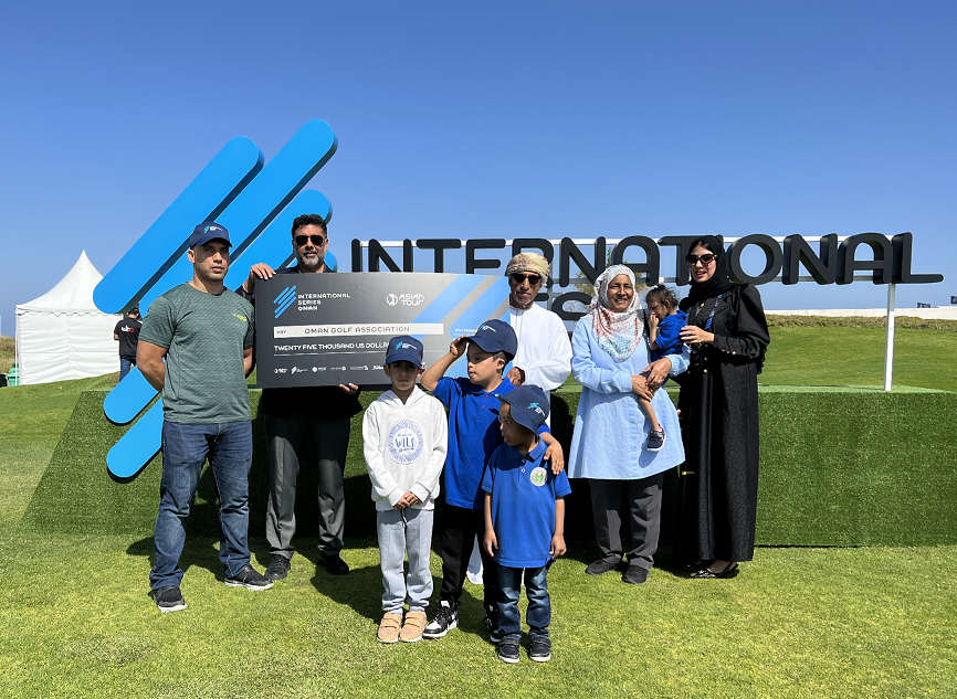 Rahul Singh , Head of The International Series, hands a $25,000 donation to Chairman of the Oman Golf Association, Mundhir Al Barwani, as children and women from benefiting charities gather at Al Mouj Golf