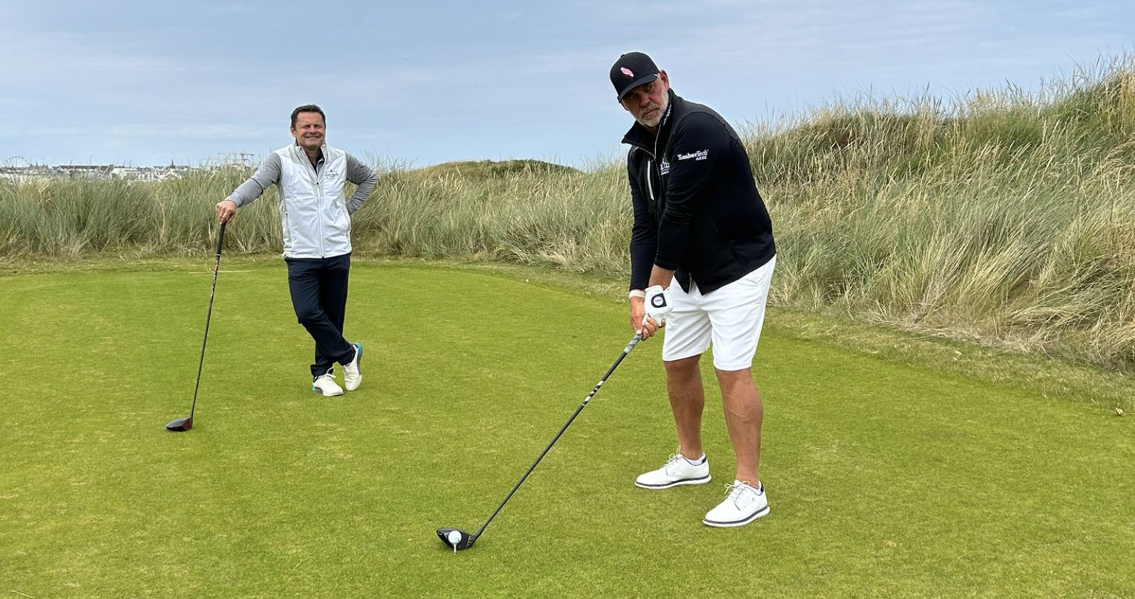 Darren Clarke prepares to tee off on the first hole at Royal Portrush, watched on by Chris Hollins, for the next series of TV show Golf"s Greatest Holes