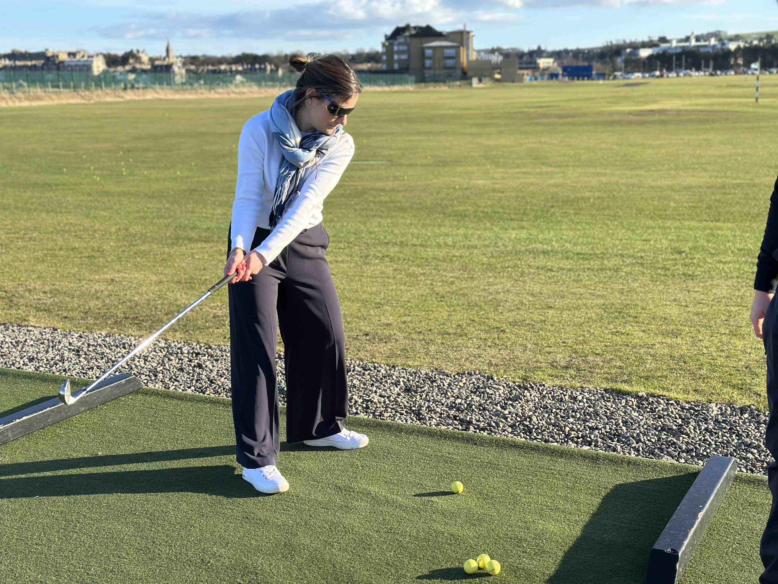 A coach with sim specs on practices her swing on the driving range at St Andrews