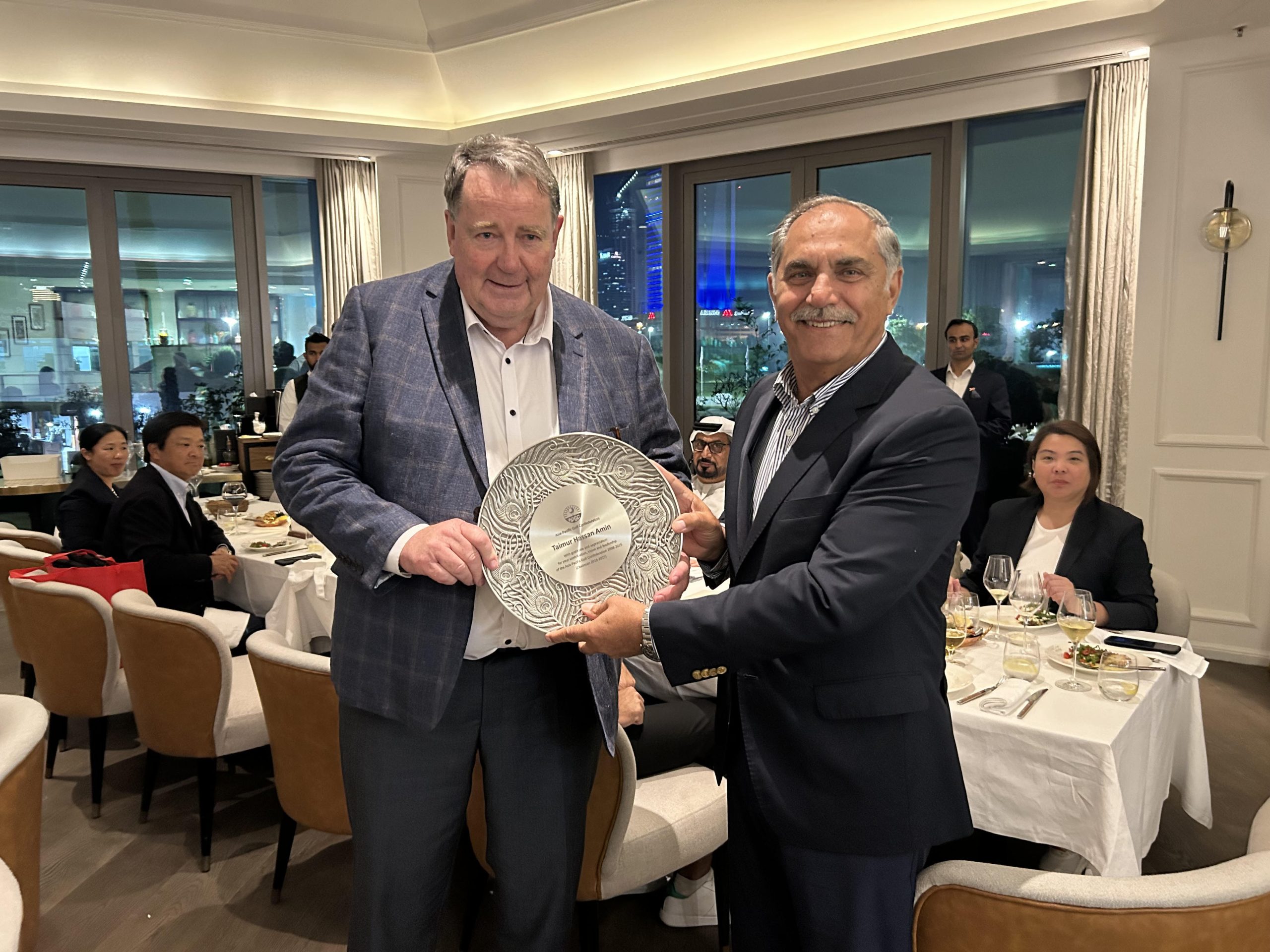 Taimur Hassan Amin is presented  by Philip Hassall with a plaque and a commemorative photo montage of his time in office