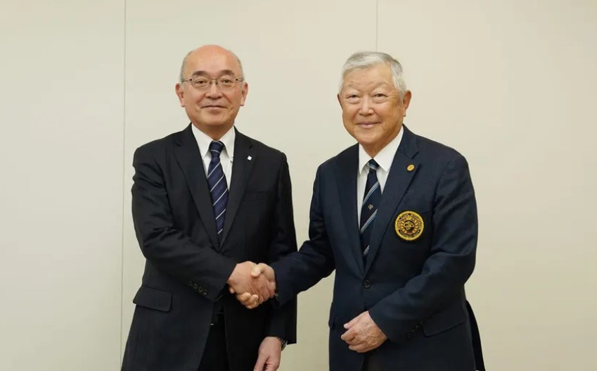 Japan Golf Association Chairman Masanari Iketani (right) shakes hands with Shinkin Central Bank President Hiroyuki Shibata.